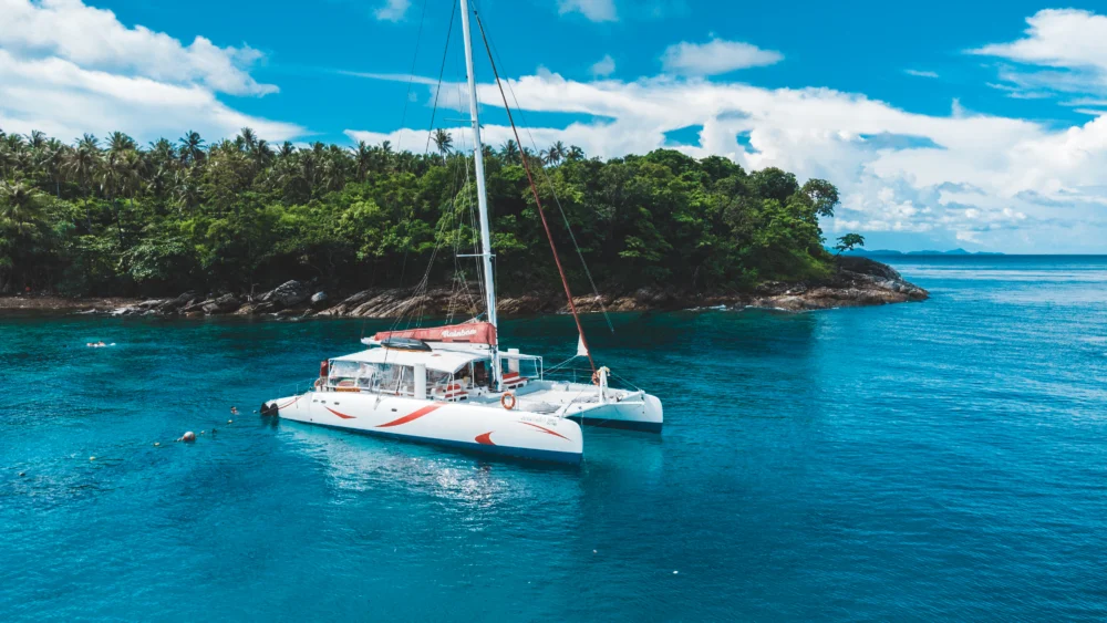 Smile Rainbow Catamaran cruising in turquoise water near Phuket islands