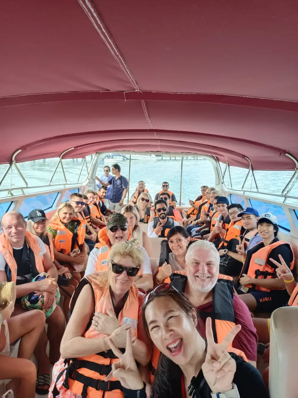 Tour guide and passengers sharing a group moment inside a Phuket speedboat