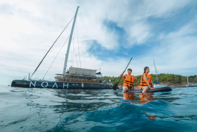 Paddleboarding beside Noah Catamaran at Racha Island