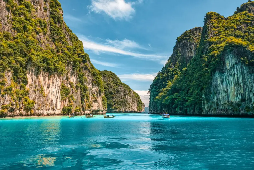 Long-tail boat in clear water surrounded by limestone cliffs at Pileh Lagoon