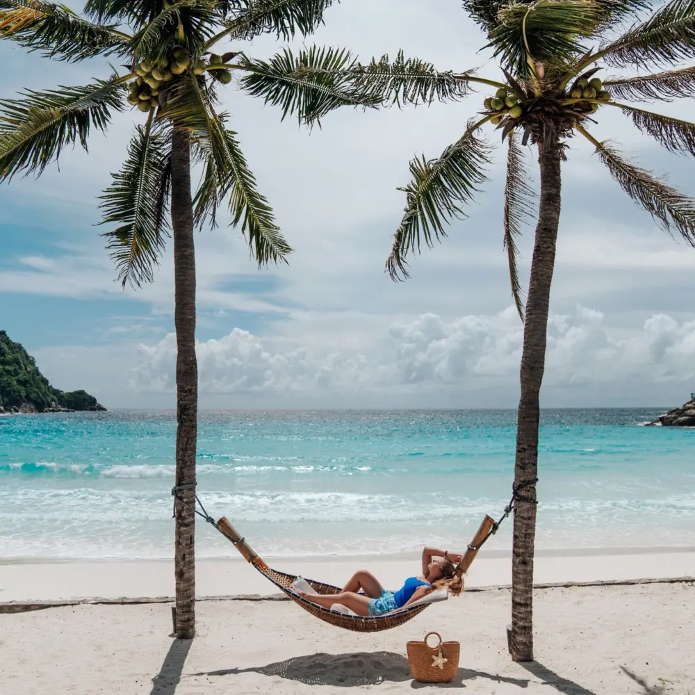 Woman resting in a hammock while looking toward Patok Beach on Racha Island
