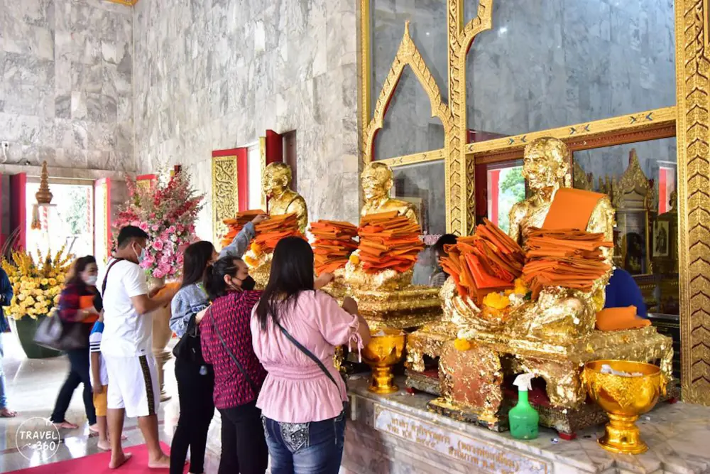 Visitors praying and applying gold leaf at Wat Chalong Phuket