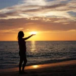 Silhouette of a woman posing with the setting sun at Karon Beach