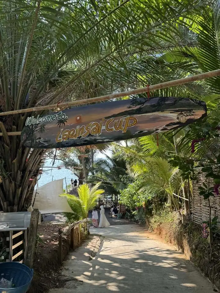 Leafy entrance path and wooden sign at Laem Sai Cup Cafe