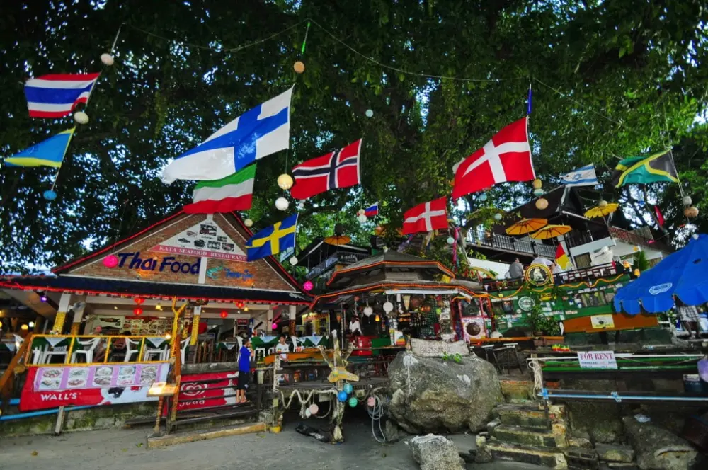 Colorful flags, signs and shaded seating at Ska Bar beside Kata Beach