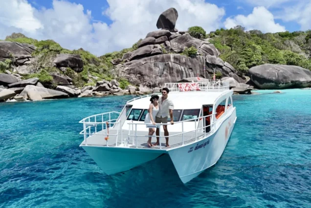 Guests on the Once catamaran bow with Sailing Rock behind
