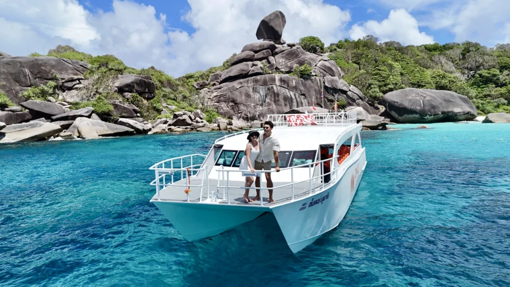 Guests on the Once catamaran bow with Sailing Rock behind