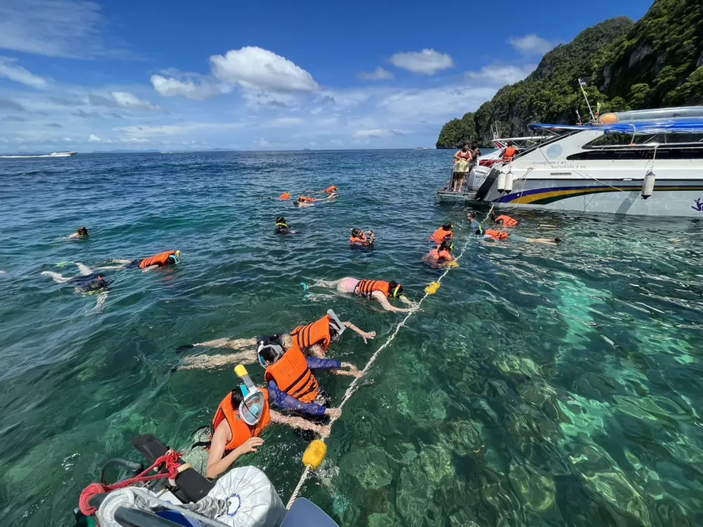 Travellers holding a guide line while snorkeling together in the Phi Phi Islands