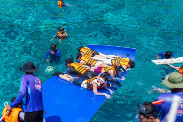 Guests snorkeling with a floating mat beside the Seastar Rainbow catamaran