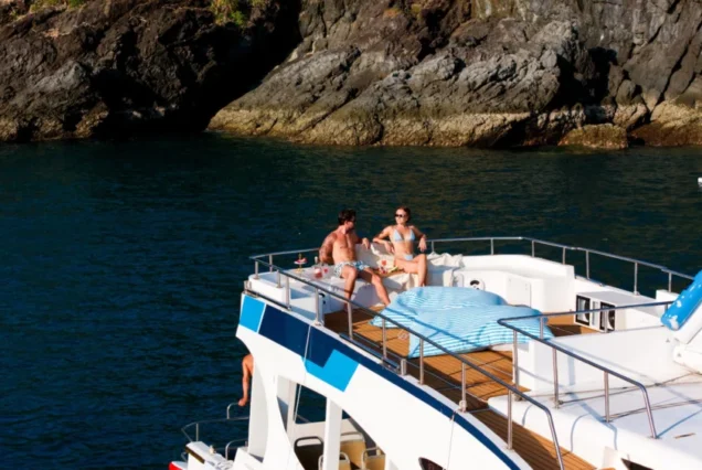 Guests relaxing on the upper deck of Taurus near an island coast
