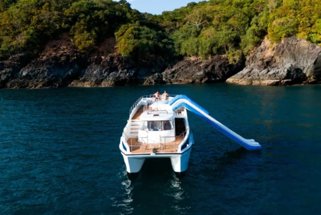 Taurus anchored near a rocky island coast with its waterslide extended