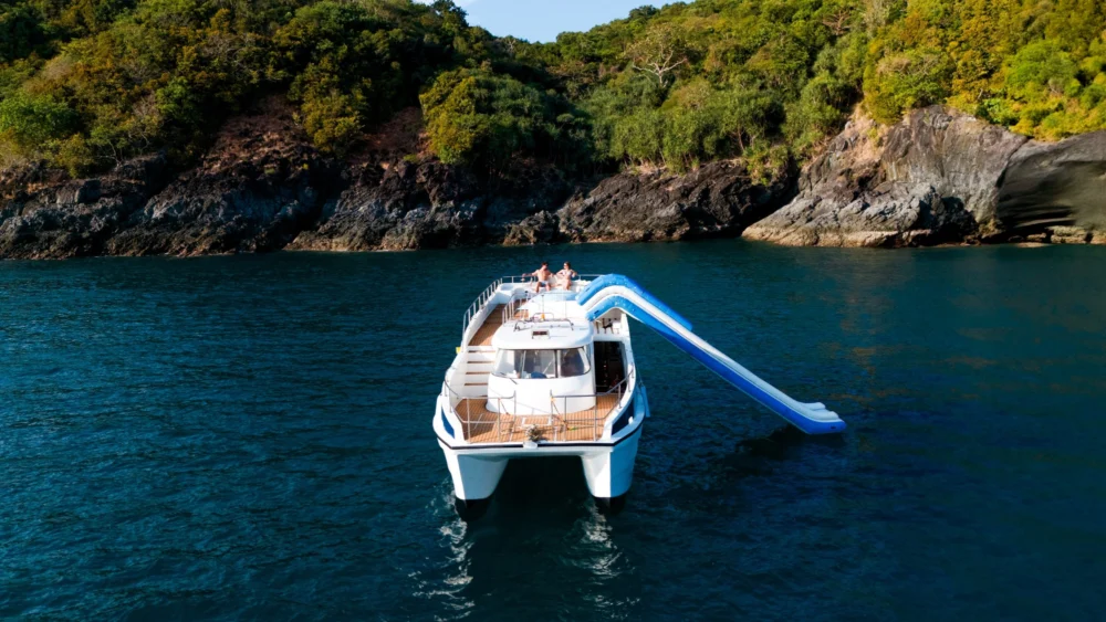 Taurus anchored near a rocky island coast with its waterslide extended